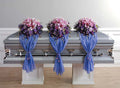 Purple funeral flower arrangements with blue drapes on silver casket, Joshua's Greenery