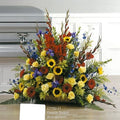Colorful funeral flower arrangement with sunflowers, roses, and lilies by Joshua's Greenery