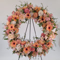 Large floral wreath with peach gerbera daisies and roses, arranged by Joshua's Greenery Barrie Florist.