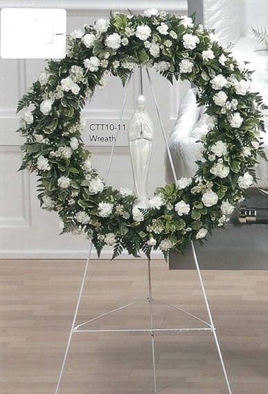 Large white and green funeral wreath with statue, displayed on metal stand at Joshua's Greenery Barrie Florist.