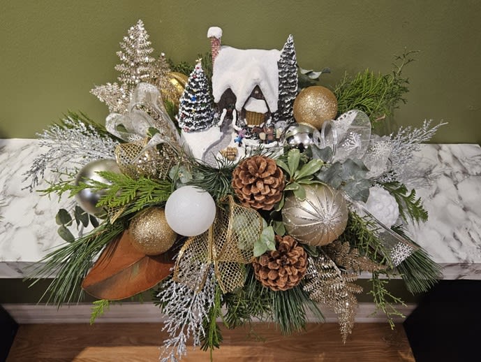 Festive winter centerpiece with snowy house, pinecones, ornaments, and greenery from Joshua's Greenery Barrie Florist.