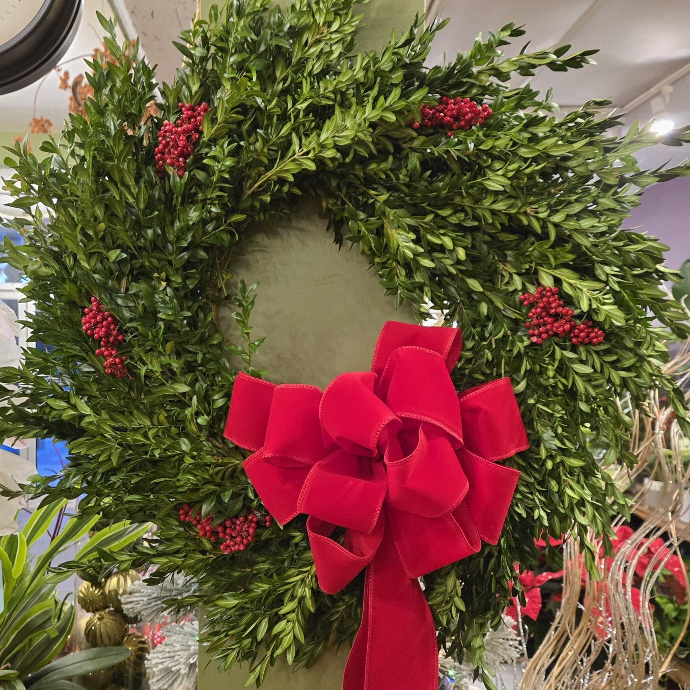 Holiday greenery wreath with red berries and large red bow at Joshua's Greenery-Barrie Florist