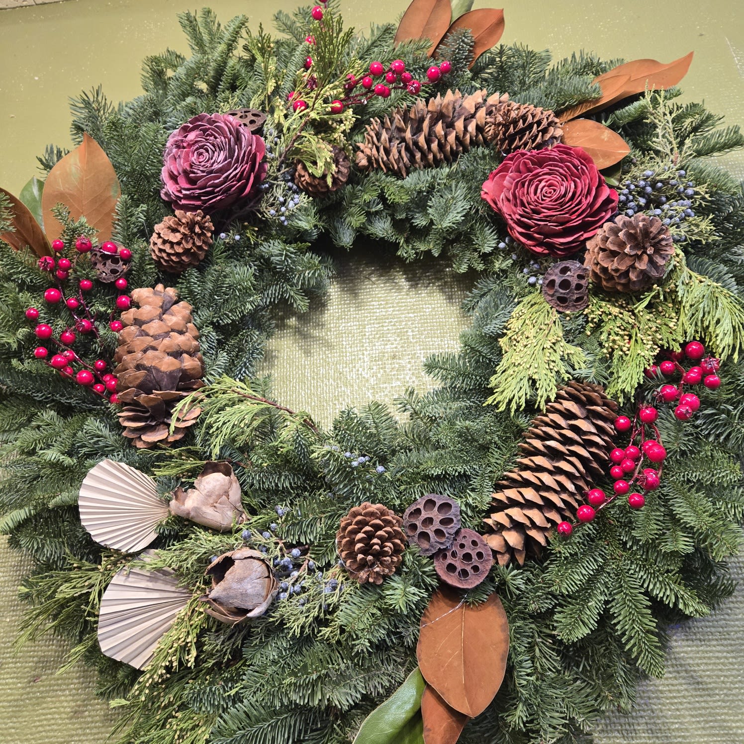 Festive holiday wreath with pinecones, red berries, and greenery from Joshua's Greenery Barrie Florist