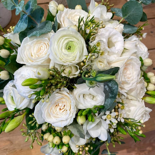 White rose bouquet with greenery from Joshua's Greenery Barrie Florist on wood surface