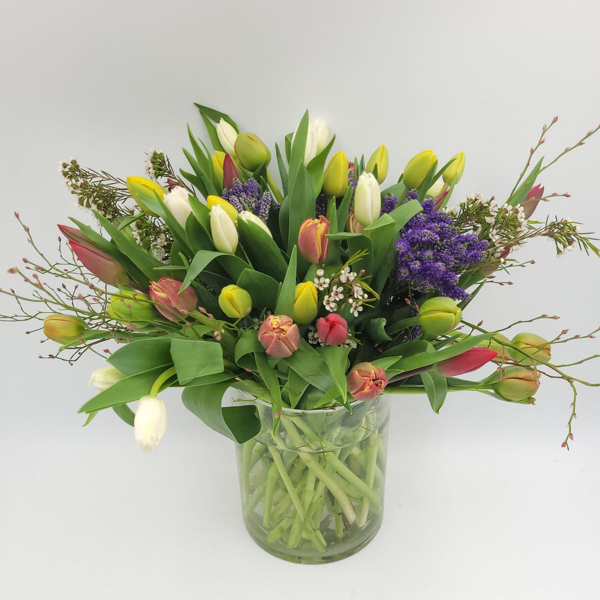 Mixed tulip bouquet in glass vase from Joshua's Greenery Barrie Florist on white background