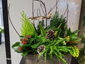 Festive winter planter with greenery, pine cones, red flowers, and decorative bird by Joshua's Greenery Barrie Florist