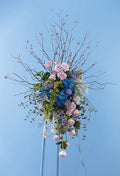 Elegant floral arrangement with pink roses, blue hydrangeas, and greenery on easel, Joshua's Greenery