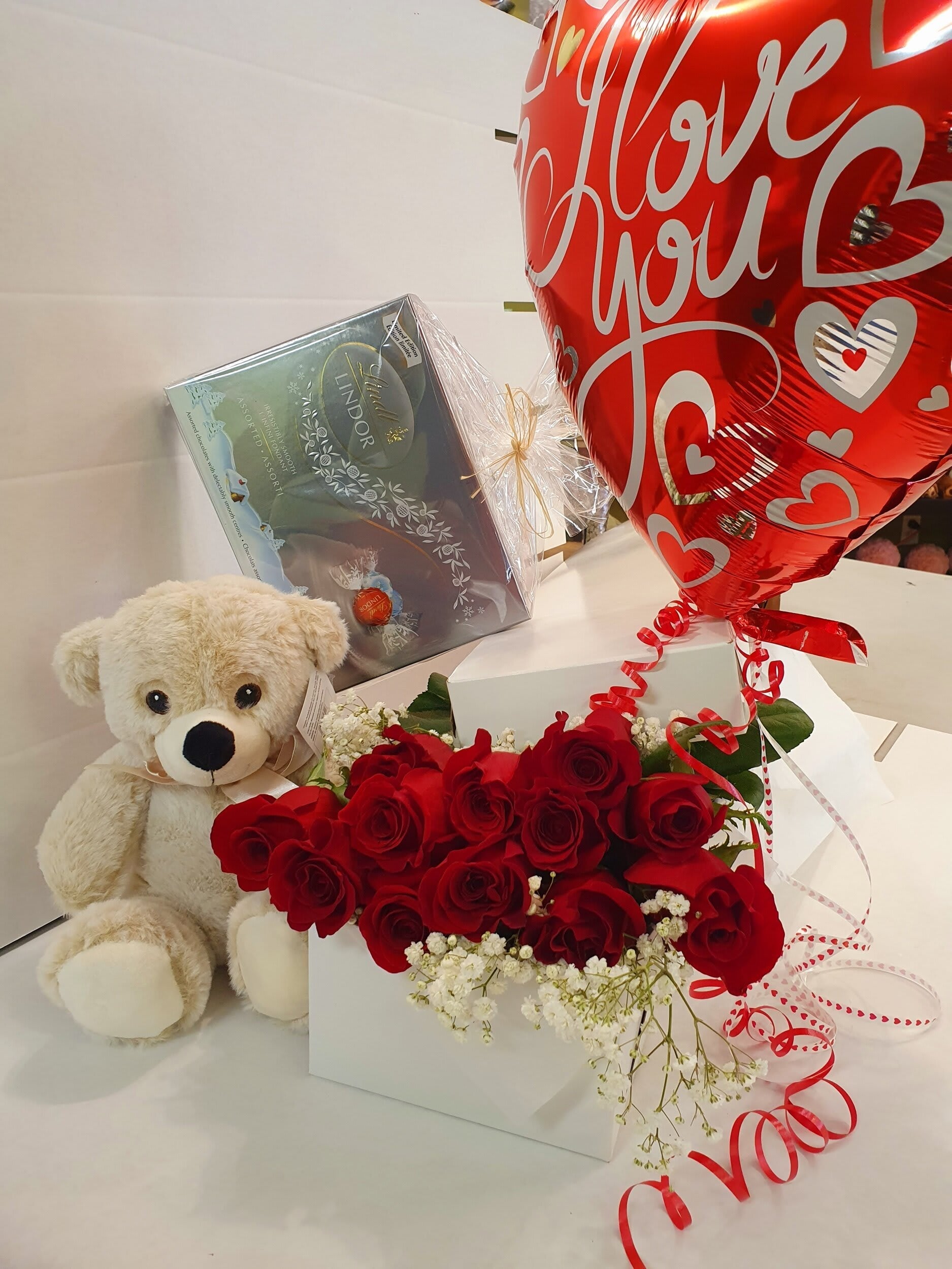 Red roses in a box with baby's breath, teddy bear, Lindor chocolates, and heart balloon, Barrie florist gift.
