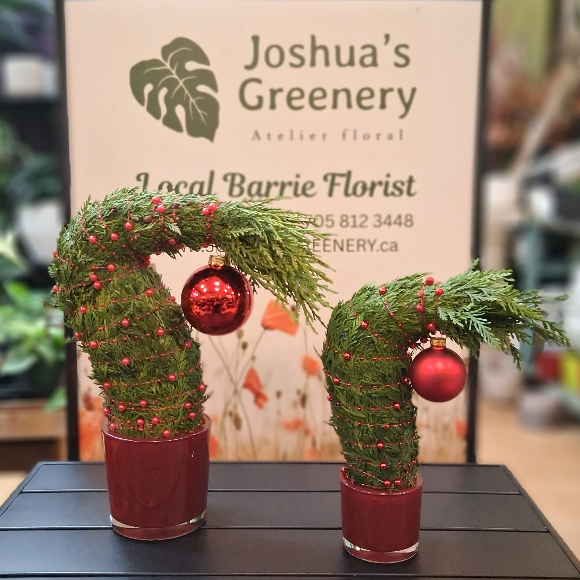 Festive Grinch-style Christmas greenery arrangements with red ornaments at Joshua's Greenery Barrie Florist